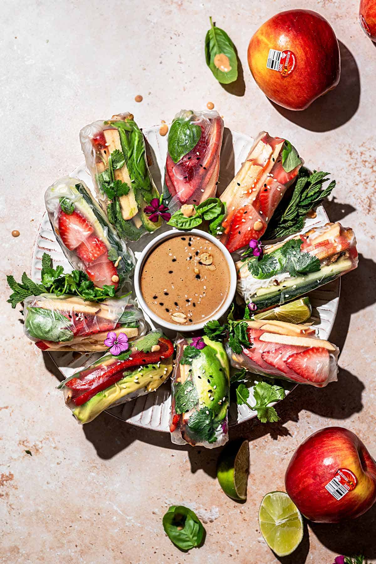 Vegan summer rolls on a serving plate around peanut sauce.