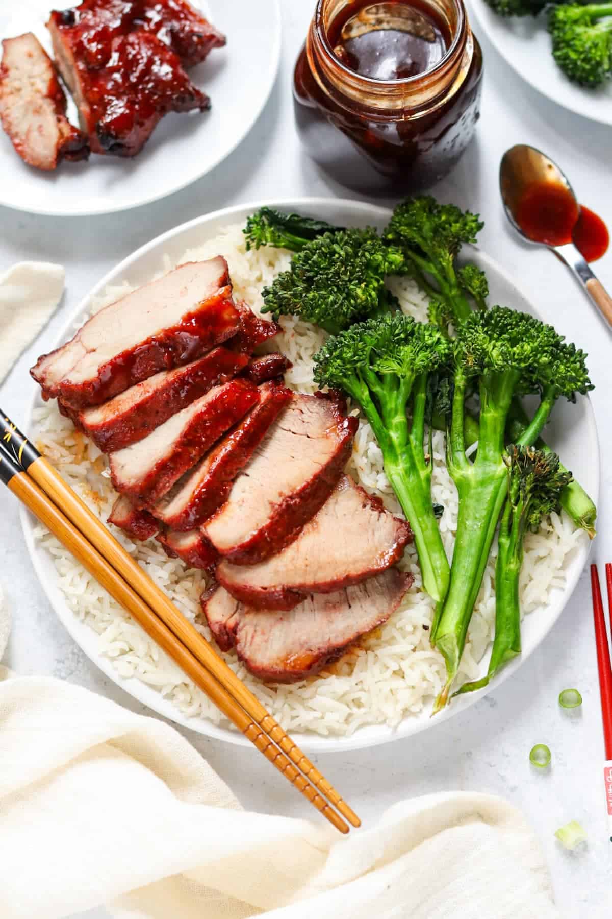 Slices of Char Siew next to vegetables on a white plate.