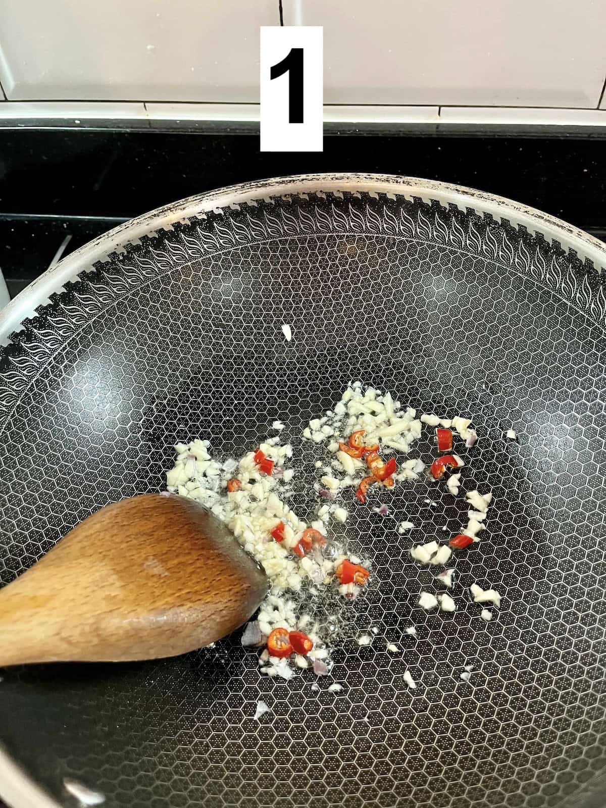 Sit frying minced garlic and minced chicken in a wok.
