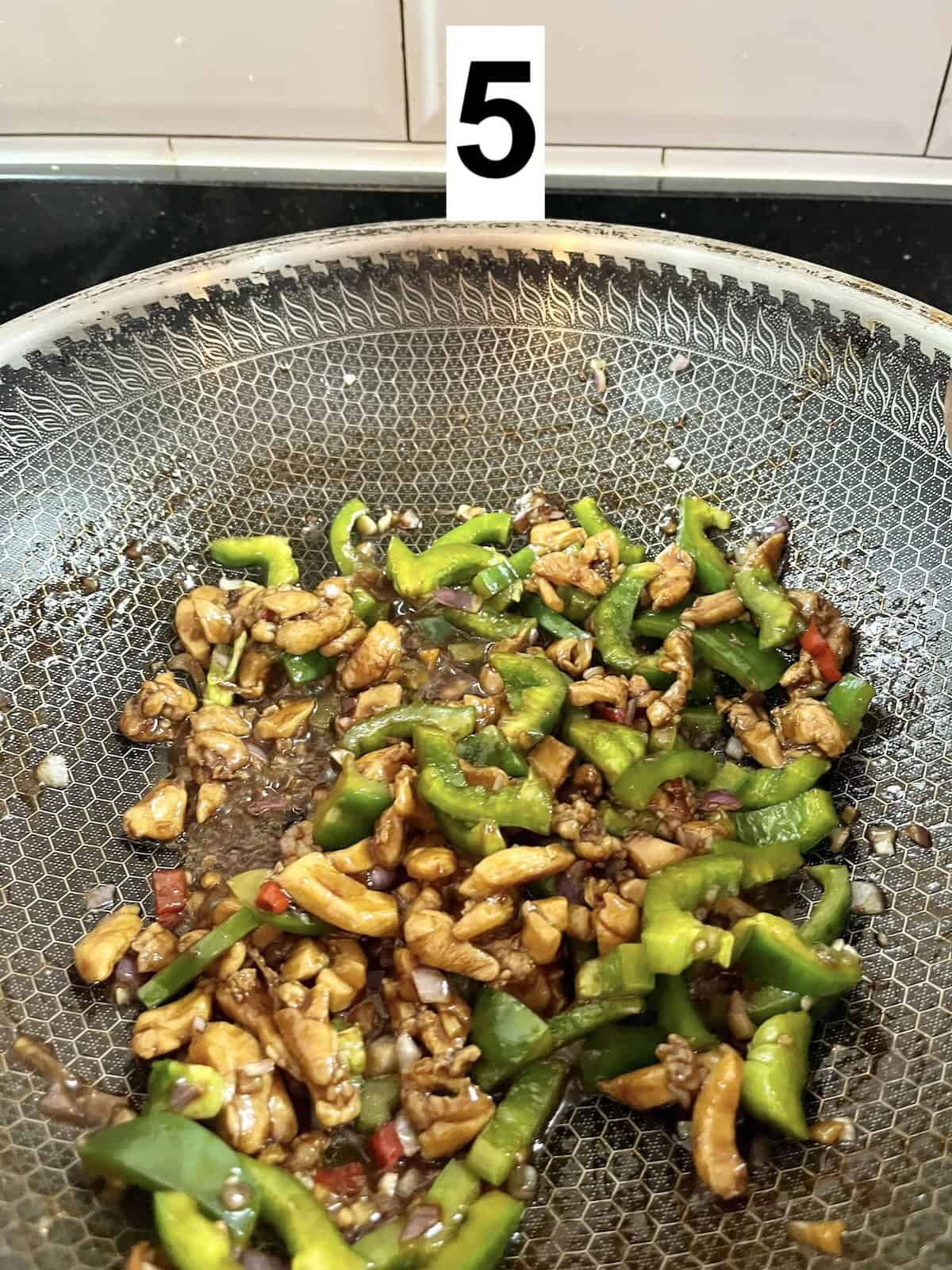 Stir fried green peppers and chicken in a wok.