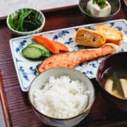 A traditional japanese breakfast of rice, pickles, and fish on a tray.