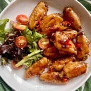 Teriyaki chicken wings and Japanese salad on a white plate.