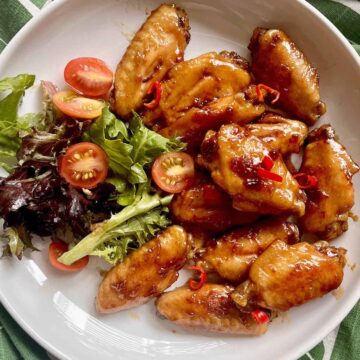 Teriyaki chicken wings and Japanese salad on a white plate.
