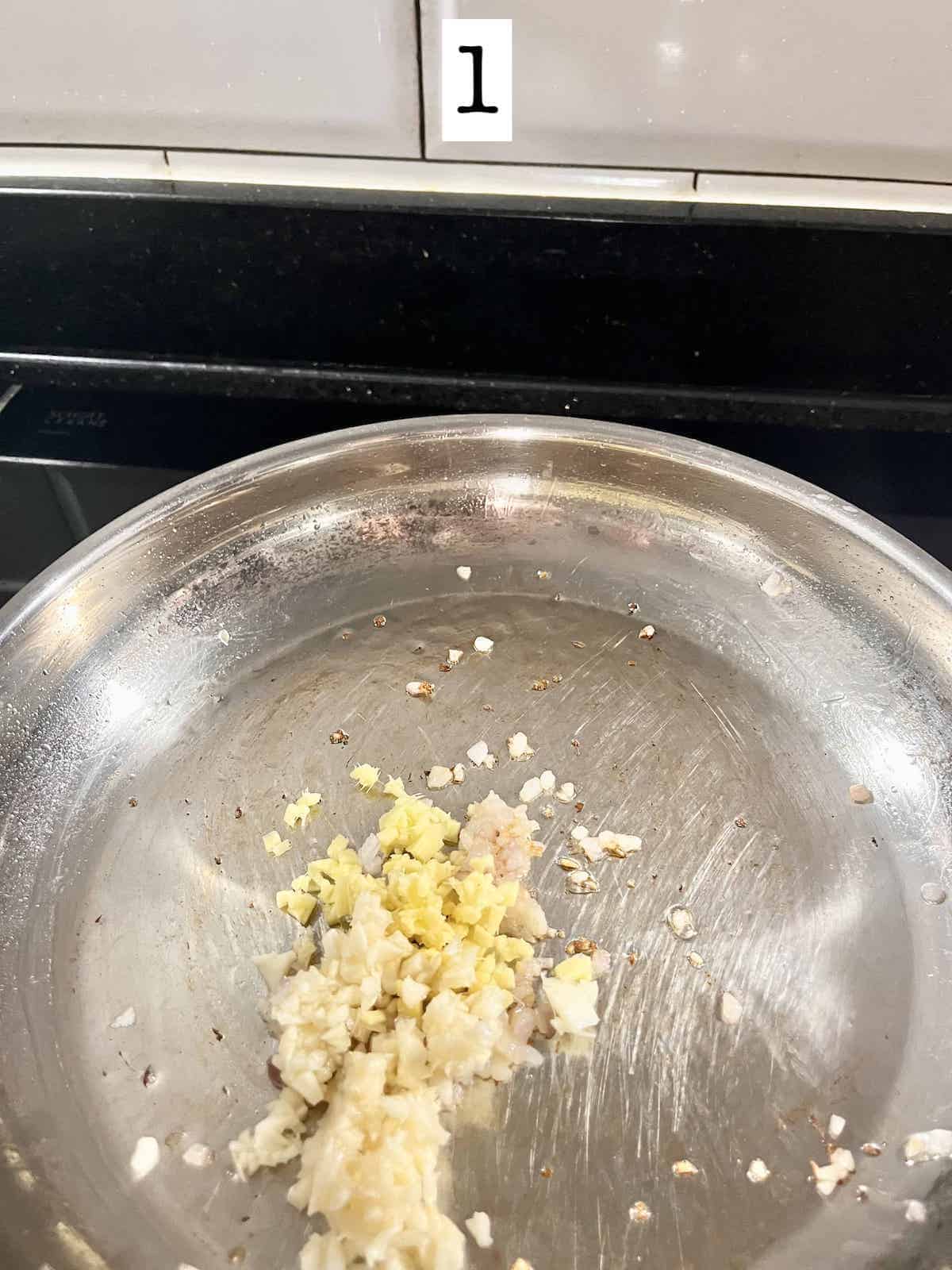 Stir-frying minced garlic, minced ginger, and minced onions in a pan.