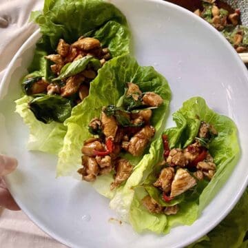 3 Thai chicken lettuce wraps on a white plate.