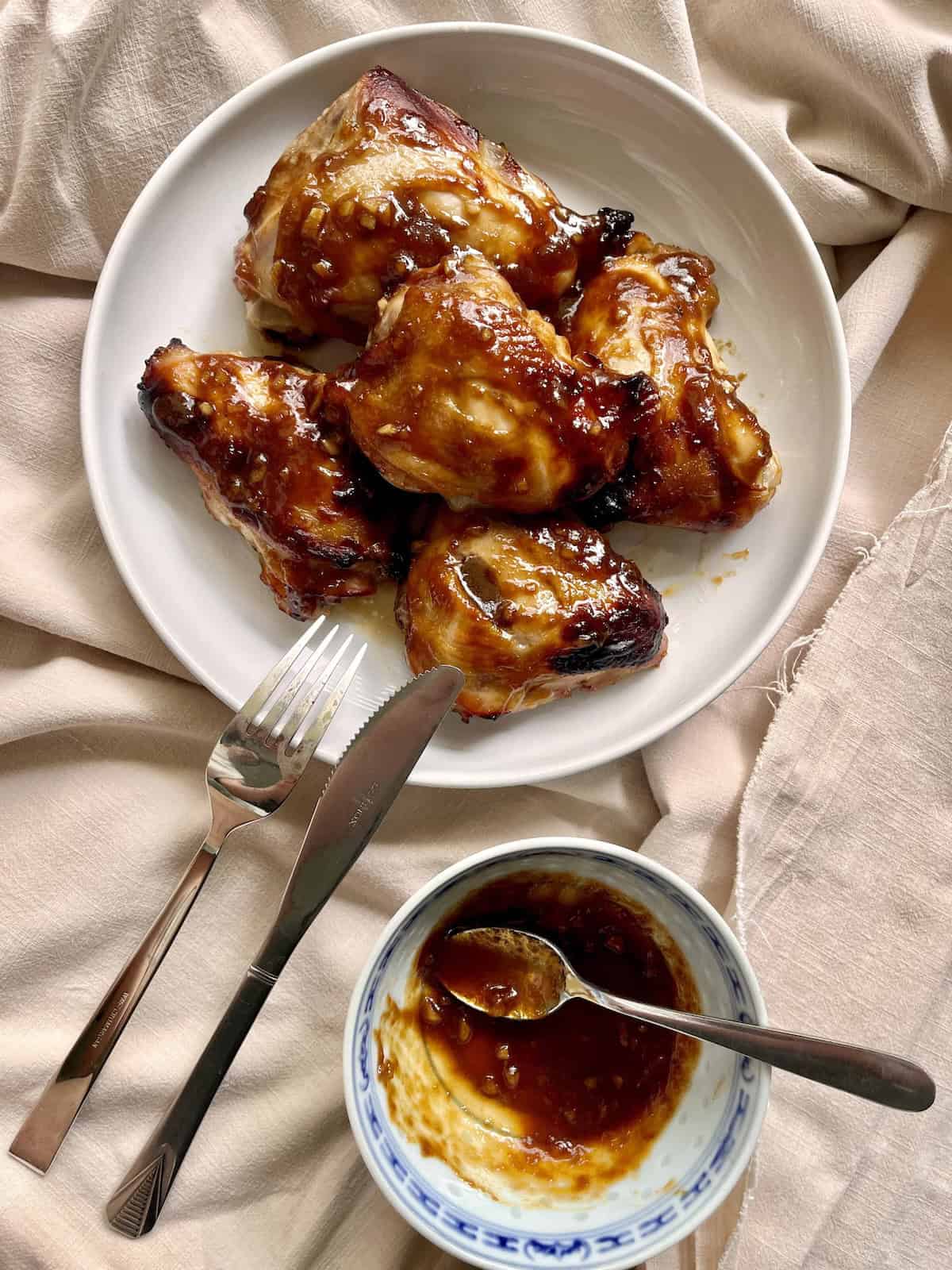 5 pieces of baked Char Siu Chicken thighs with a sauce glaze in a bowl.