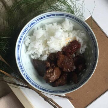 A bowl of Filipino braised adobo pork belly and white rice.