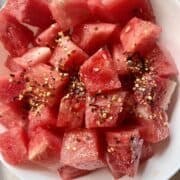 Fresh cut watermelon salad with chili flakes in a white bowl.