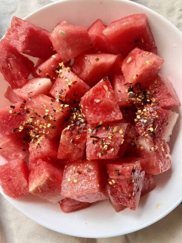Fresh cut watermelon salad with chili flakes in a white bowl.