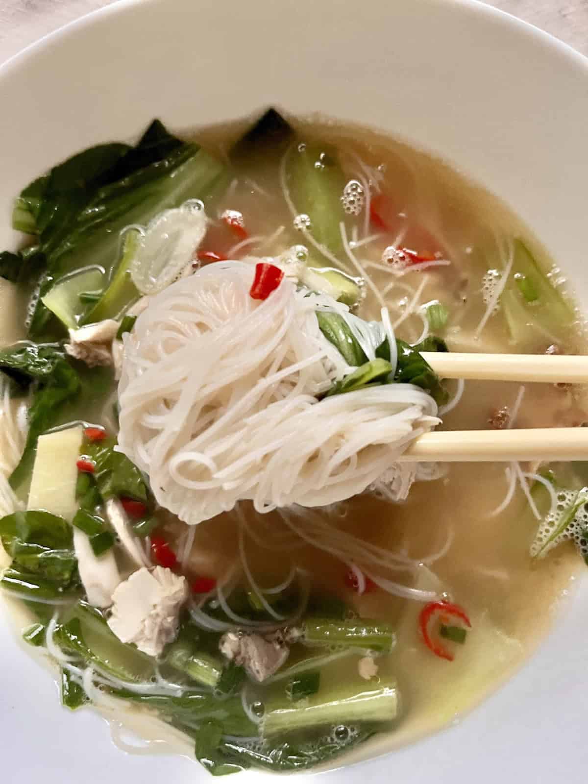 Taking leftover roast chicken noodle soup with chopsticks.