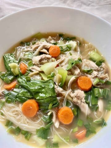 Shredded roast chicken rice noodle soup with carrot and green vegetables.