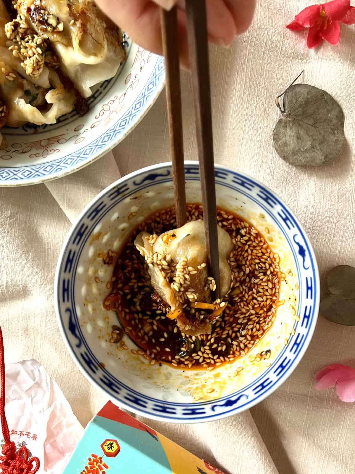 Dipping Chinese dumpling into sauce.