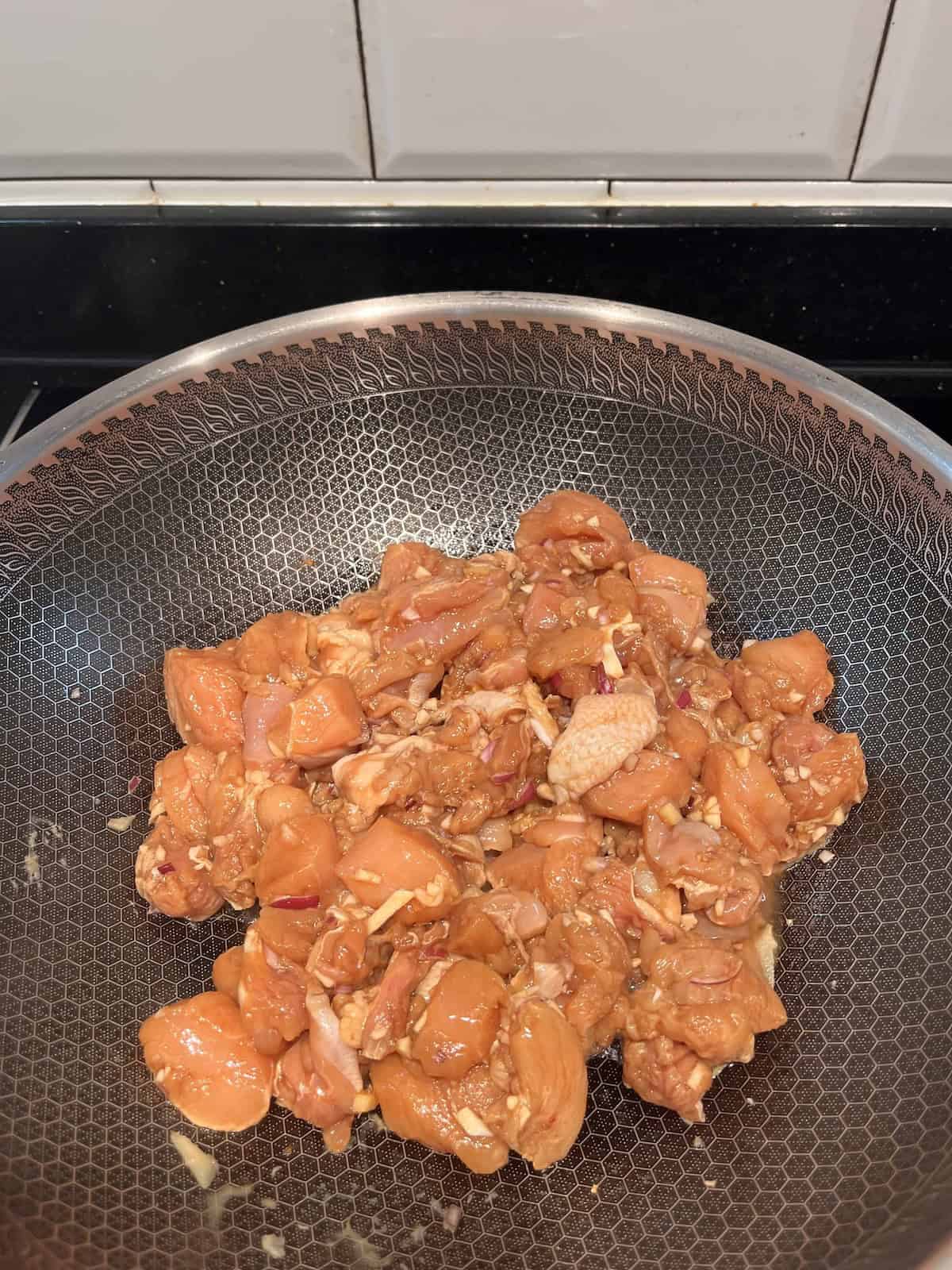 Boneless, skinless chicken thigh in a wok.