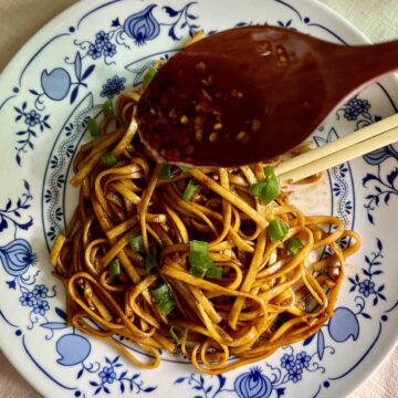 A plate of spicy Chinese noodles with chili oil.