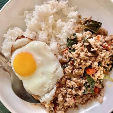 Stir fried Thai Basil Pork Pad Gra Pao and fried egg on white rice.