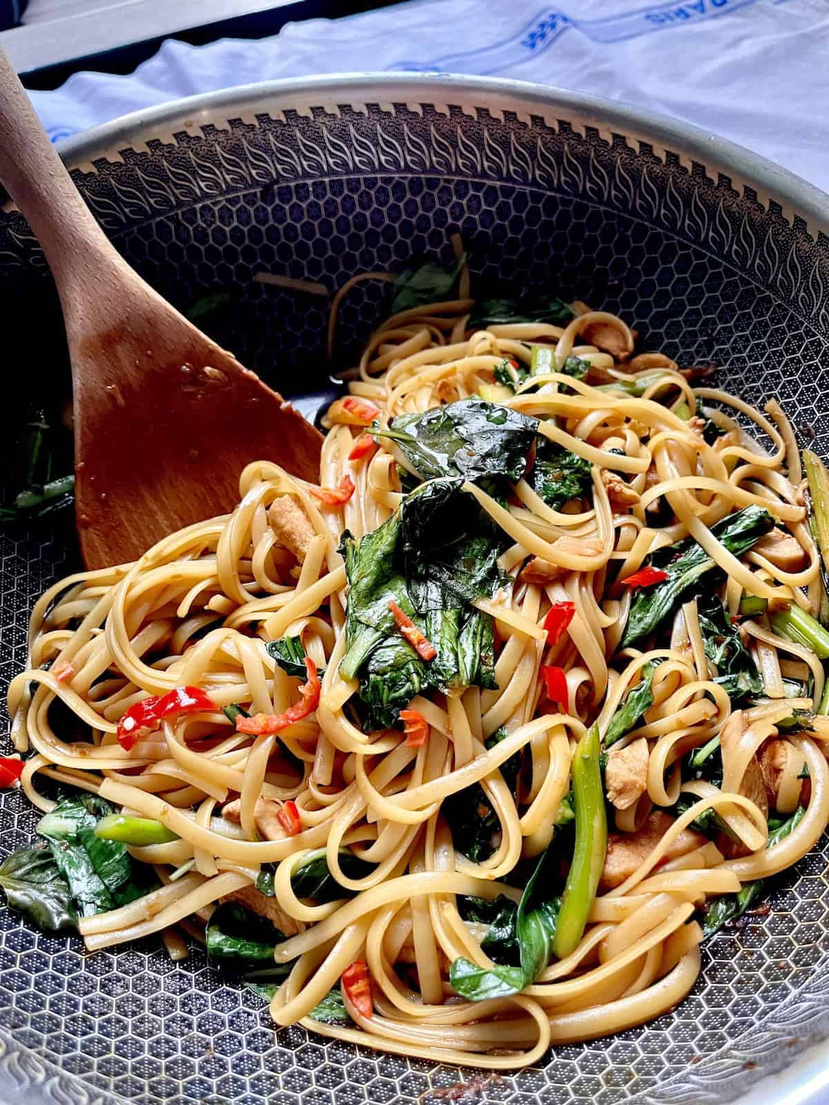 Thai Drunken Noodles with chicken in a wok.