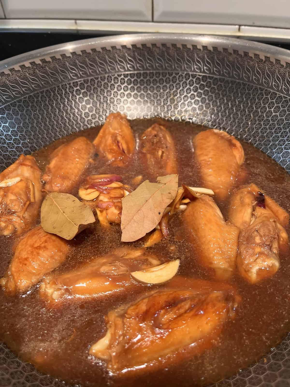 Braising chicken wings in Filipino adobo sauce.