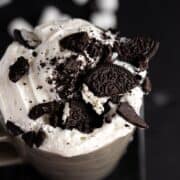 Oreos and cream on a mug of chocolate.