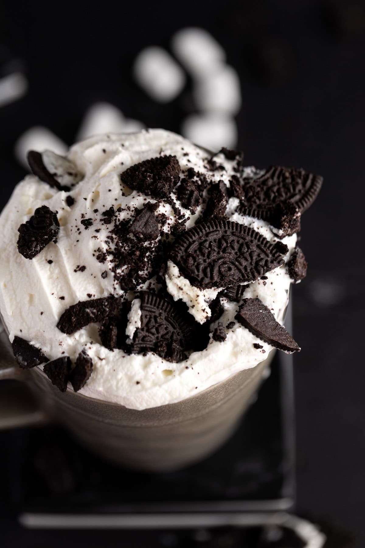Oreos and cream on a mug of chocolate.