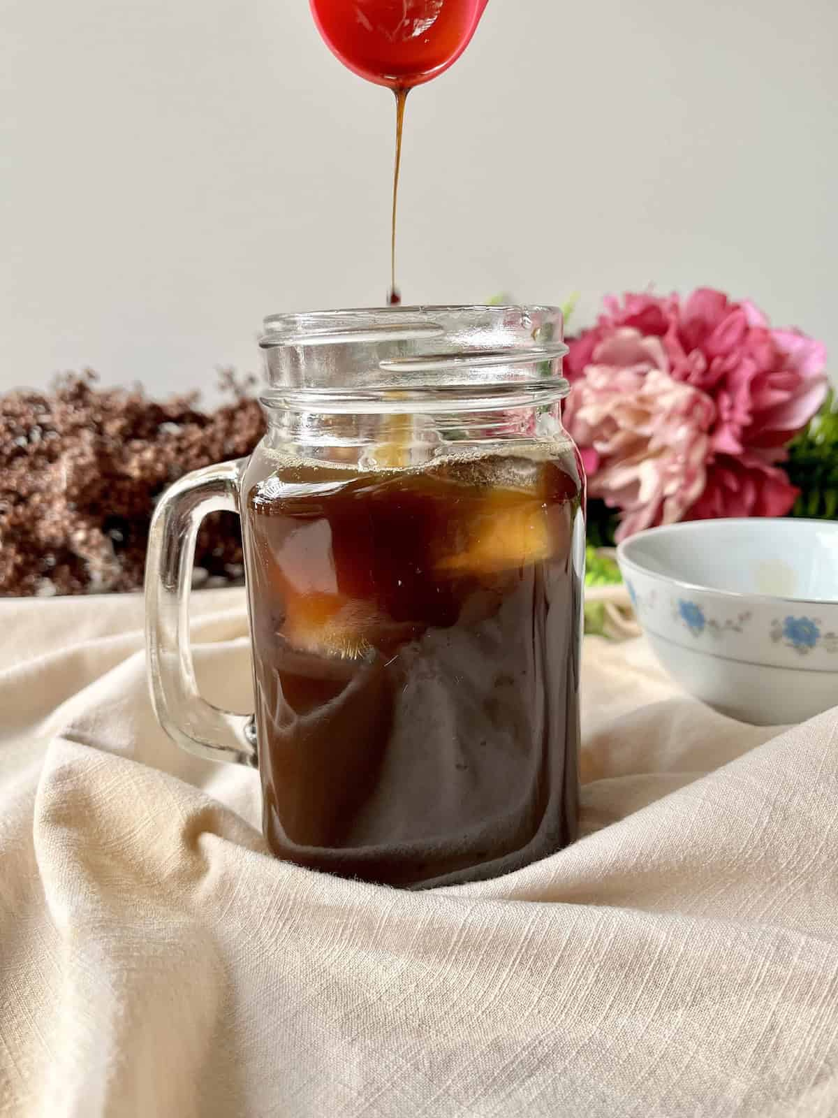 Dripping syrup into a mug of iced latte.
