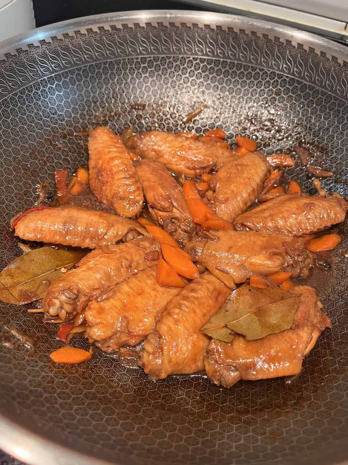Chicken wings and carrots in a wok.