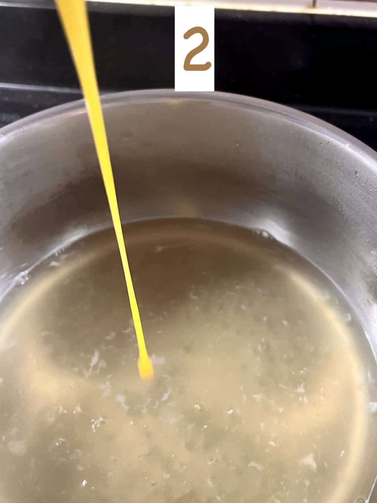 Pouring whisked egg into a pot of chicken broth,