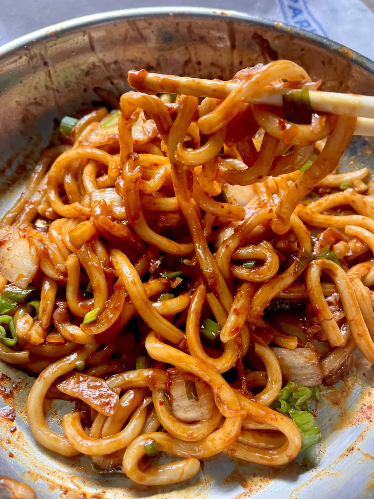 Stir fried kimchi udon in a pan.