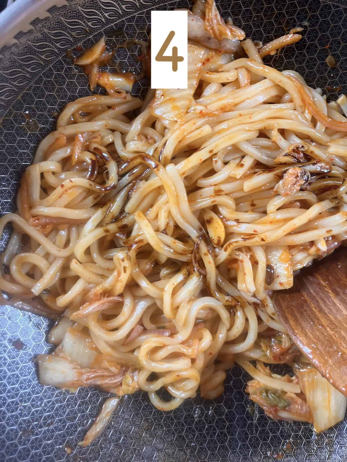 Adding dark soy sauce to kimchi udon.
