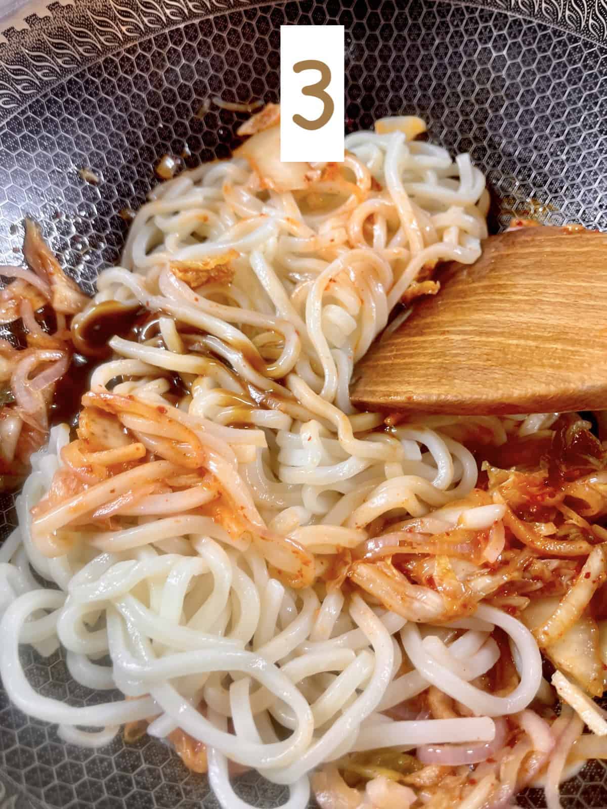Adding oyster sauce to udon and kimchi.