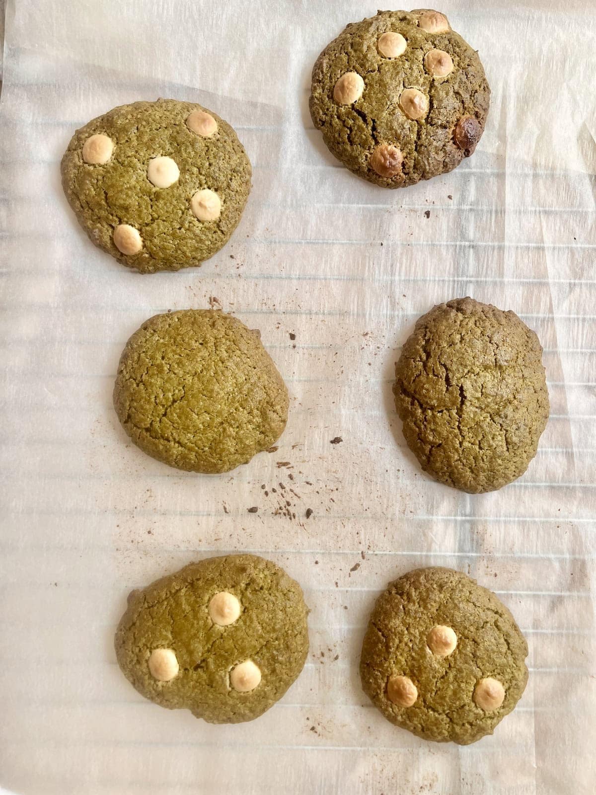 Overbaked Matcha cookies with white chocolate on a baking tray.