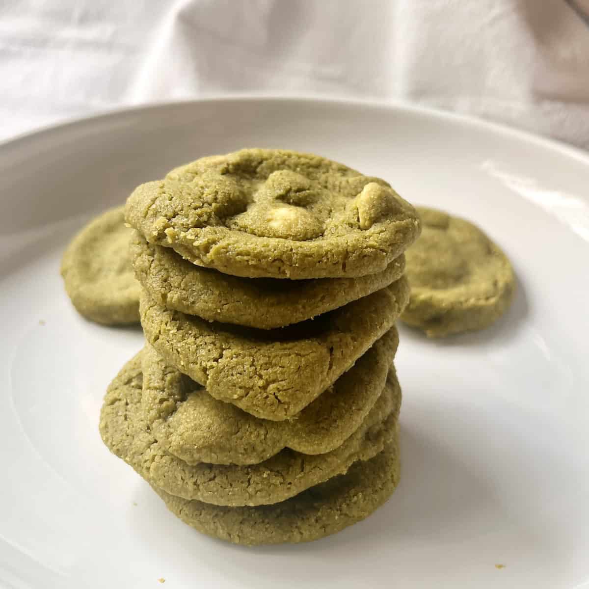 A pile of matcha white chocolate cookies on a white plate.