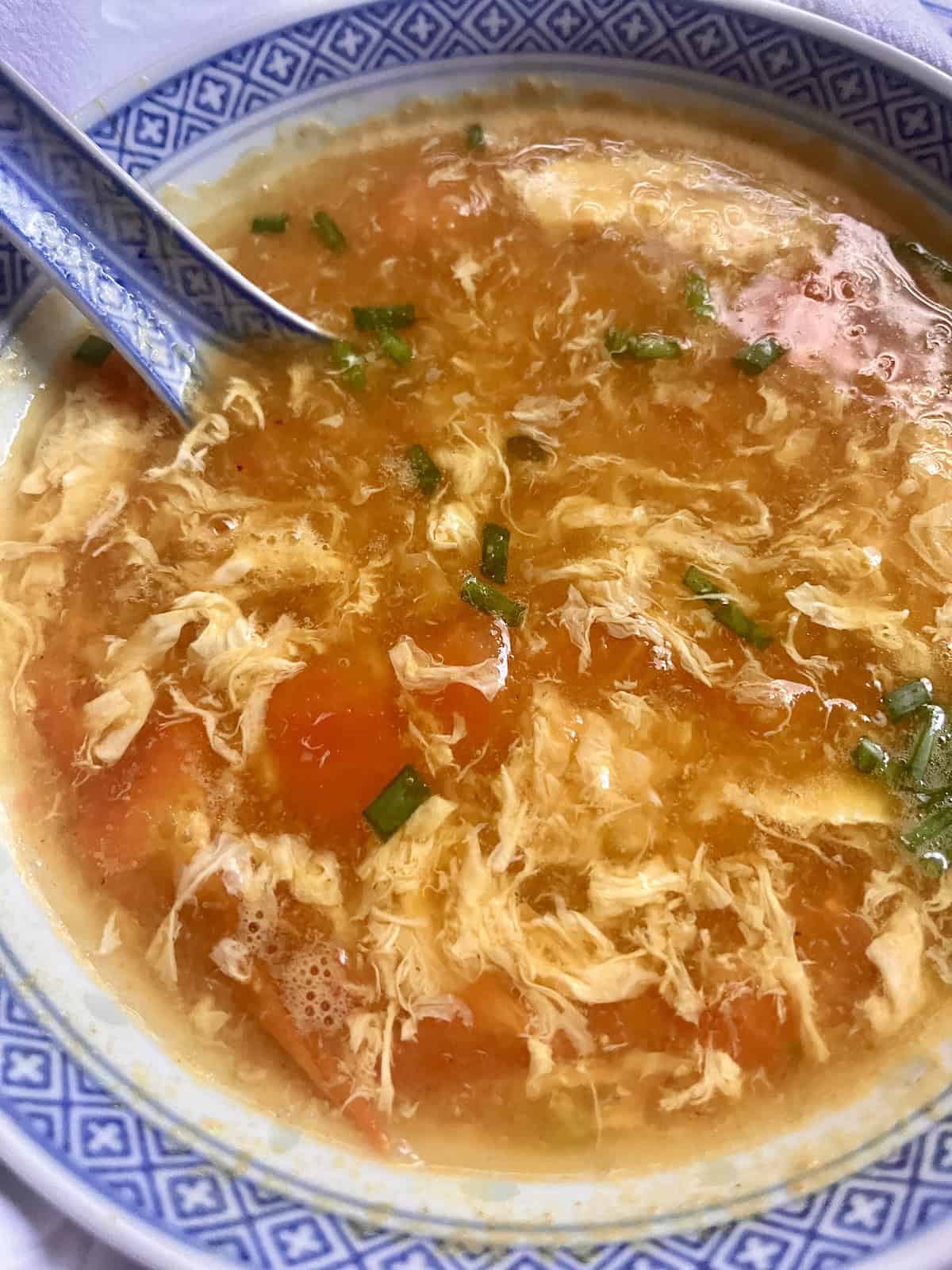 A bowl of Chinese egg drop soup with tomatoes.